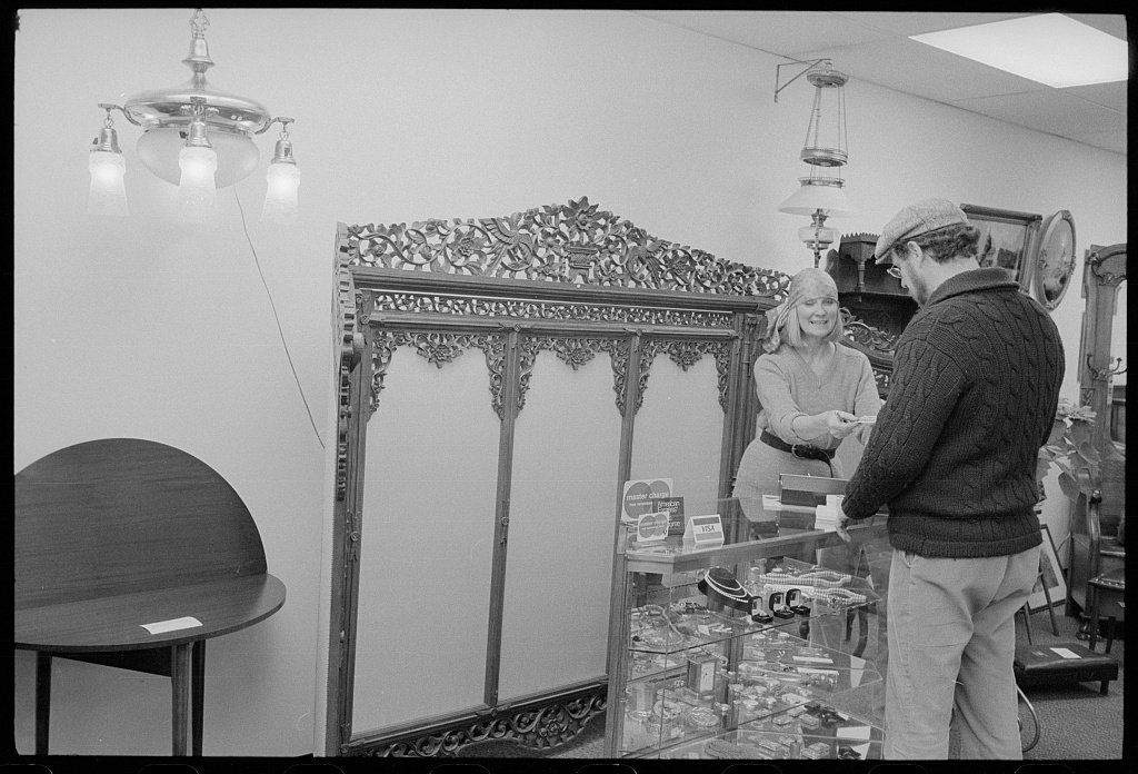 Black-and-white photograph of a man using a credit card at a store counter, United States, 1979